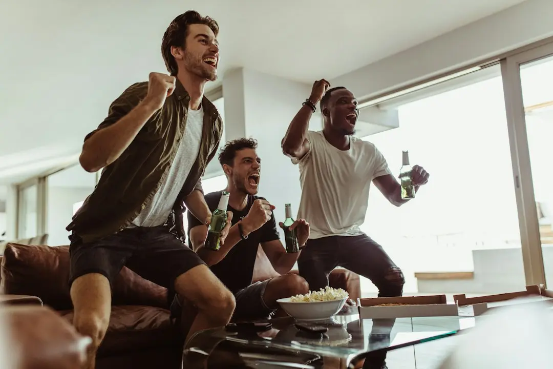 Friends on a sofa cheering at a game on television, watching live sports with AlwaysTivi